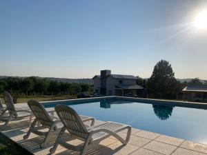 a swimming pool with four chairs and the sun at Cabañas Sonnenblumen in Potrero de Garay