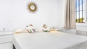 a white bedroom with a bed with a mirror on the wall at Anc 13 BP - Llafranc in Calella de Palafrugell