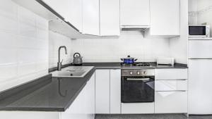 a white kitchen with a stove and a sink at Anc 13 BP - Llafranc in Calella de Palafrugell +14 photos