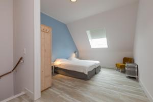 a bedroom with a bed and a blue wall at Ride by the Sea Guesthouse in Koudekerke