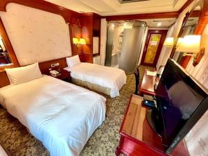 a hotel room with two beds and a flat screen tv at Meadow Hotel Taipei in Taipei