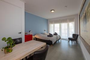 a bedroom with a bed and a table and chairs at Ride by the Sea Guesthouse in Koudekerke