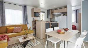 a kitchen and living room with a table and a couch at Domaine du Blanc Pignon in La Calotterie