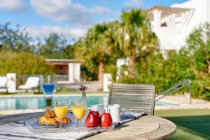 a table with a plate of food and two glasses of orange juice at Villa Munt Blanc Ibiza in Puig D’en Valls