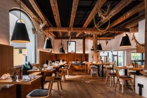 un restaurante con mesas y sillas de madera y colgantes negros en Hotel & Restaurant Posthalterei en Zusmarshausen