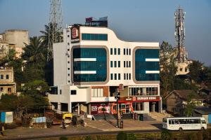 a white building with a bus in front of it at Hotel Jurkis, Kolhapur in Kolhapur