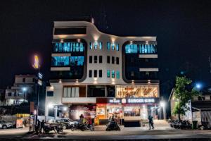 ein hohes Gebäude mit Menschen, die nachts draußen stehen in der Unterkunft Hotel Jurkis, Kolhapur in Kolhapur
