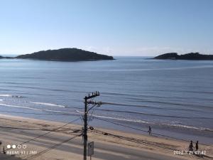 a beach with people walking on the sand and the ocean at APARTAMENTO PIUMA in Piúma