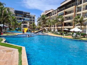 a swimming pool with palm trees and a slide at Beach Living Vista Mar - 3 Quartos - Pé na Areia in Aquiraz