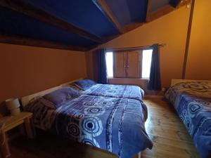 a bedroom with two beds and a window at La Casita Violeta in Santa María de la Alameda