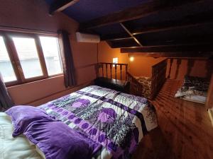 ein Schlafzimmer mit einem Bett mit einer lila Bettdecke in der Unterkunft La Casita Violeta in Santa María de la Alameda