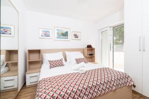 ein weißes Schlafzimmer mit einem Bett und einem Fenster in der Unterkunft Villa Stipe in Stari Grad