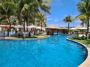 a pool at the resort with palm trees and umbrellas at Beach Living Vista Mar - 3 Quartos - Pé na Areia in Aquiraz