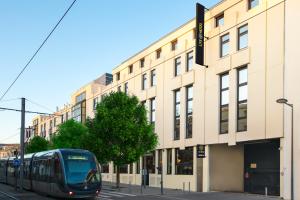 a train on a street in front of a building at Hôtel Life Bordeaux Gare - BG in Bordeaux