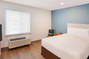 WoodSpring Suites Pharr في فار: غرفة نوم بسرير ابيض ونافذة