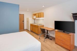 een hotelkamer met een bed en een bureau met een flatscreen-tv bij WoodSpring Suites Brownsville in Brownsville
