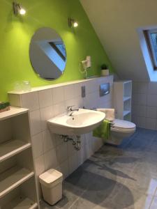 ein Badezimmer mit Waschbecken, Toilette und Spiegel in der Unterkunft Gästehaus & Ferienhof Hüfner in Speicherz