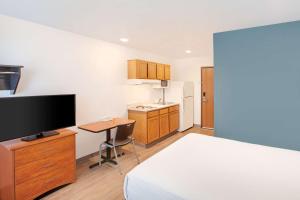 a room with a bed and a television and a kitchen at WoodSpring Suites Harlingen in Harlingen