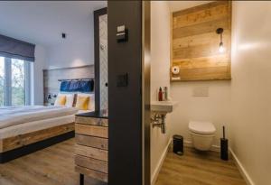 a bedroom with a bed and a bathroom with a sink at Hotel Landhafen in Niebüll