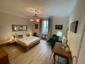 a bedroom with a bed and a desk and a table at La Maison Bleue « La Charade » in Thaon-les-Vosges