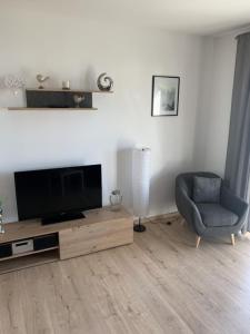 a living room with a flat screen tv and a chair at Im Blauen Ländchen in Lierschied