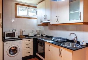 a kitchen with a sink and a washing machine at Apartamento con jardin en un chale in Bueu