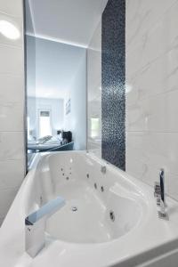 ein weißes Bad mit einer Badewanne und einem Spiegel in der Unterkunft Villa Gabriel - Dicmo in Dicmo