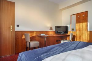 a hotel room with a bed and a desk with a television at Novum Hotel Hagemann Hamburg Hafen in Hamburg