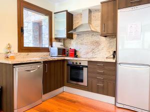 a kitchen with wooden cabinets and a white refrigerator at Apartamento moderno Pic negre con vistas in Mas de Ribafeta