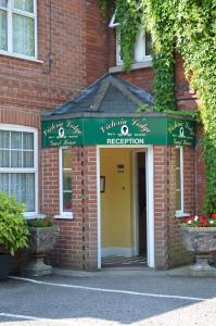 un edificio de ladrillo rojo con un cartel de recepción verde y blanco en Victoria Lodge Guest House, en Salisbury