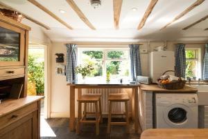 a kitchen with a counter with stools and a window at Spadgers, a flax workers cottage next to fields in a Medieval Village in Long Melford