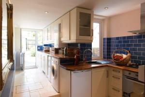 uma cozinha com electrodomésticos brancos e azulejos azuis em Meddlars a historic cottage on the countryside edge of a vibrant Market Town em Hadleigh