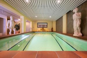 - une piscine dans un hôtel avec des statues sur le mur dans l'établissement Seilers Vintage Hotel & Spa, à Kandersteg