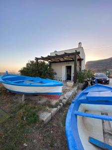 two boats are parked in front of a house at Il Cubo, monovano col mare su tre fronti. in Favignana