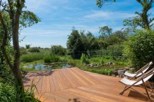 a wooden deck with a bench and a pond at Navigation Cottage on the Historic Sea Lock overlooking the Nature Reserve in Maldon