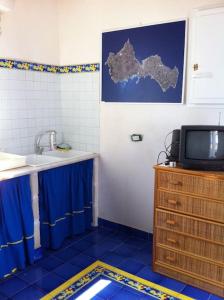 a bathroom with a sink and a tv on a cabinet at Il Cubo, monovano col mare su tre fronti. in Favignana