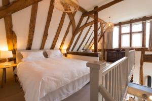 um quarto com uma cama branca num sótão em Deepwell Granary is a lovely thatched barn with attached meadow woodland em Buxhall