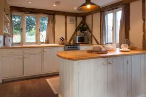 a kitchen with white cabinets and a wooden counter top at Bromans Barn a beautiful cottage by the Sea and Cudmore Nature Reserve in West Mersea