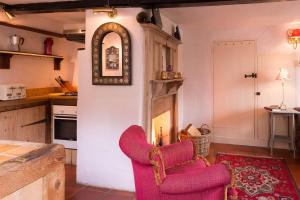 a kitchen with two chairs and a clock on the wall at Farm Cottage a cute C17th cottage a walk across the fields to a great pub 