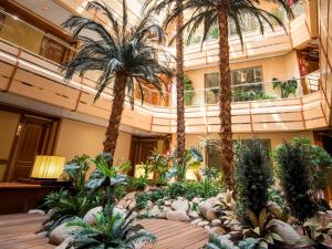 een lobby met palmbomen en planten in een gebouw bij VP Jardín Metropolitano in Madrid