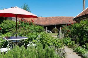 a table and chairs with an umbrella in a garden at Rose Cottage rural cosiness with footpaths to the local Macro Brewery Pub 