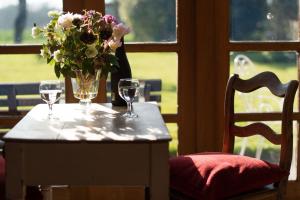 a table with two wine glasses and a vase of flowers at Dons Barn a Stunning cottage just a walk across the fields to a great pub 