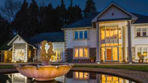 a large house with a fountain in front of a house at Plas Y Dderwen Apartments in Aberystwyth