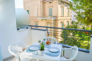 uma mesa branca e cadeiras numa varanda com um edifício em Homiday - Holiday Rendez Vous 2 em Pineto