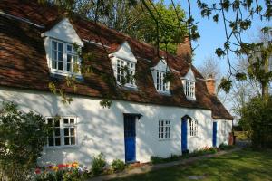 uma casa branca com portas e janelas azuis em The Wobbin, Remote, Comfort, Sea Views and the beautiful Essex Marshes em West Mersea