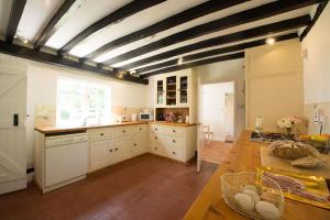 a large kitchen with white cabinets and a wooden table at The Wobbin, Remote, Comfort, Sea Views and the beautiful Essex Marshes in West Mersea