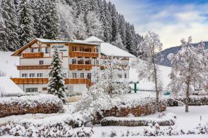 a building covered in snow in front of trees at Alpenhotel Ensmann in Göstling an der Ybbs