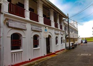 a white building with red balconies on a street at Zee Golf Affordable Luxury in Galle