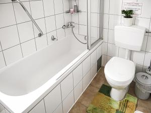a bathroom with a white tub and a toilet at Gemütliches Privatzimmer mit geteiltem Bad, Küche und Garten in Munich