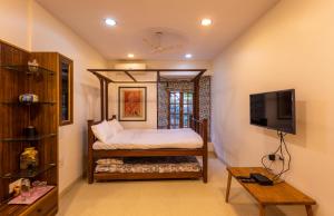 a bedroom with a bed and a tv in it at SaffronStays Birdsong, Madh - pet-friendly villa at Madh Island in Mumbai